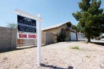 A real estate sign with a "bank owned" tag attached hangs in front of a house on Wednesday, Jun ...