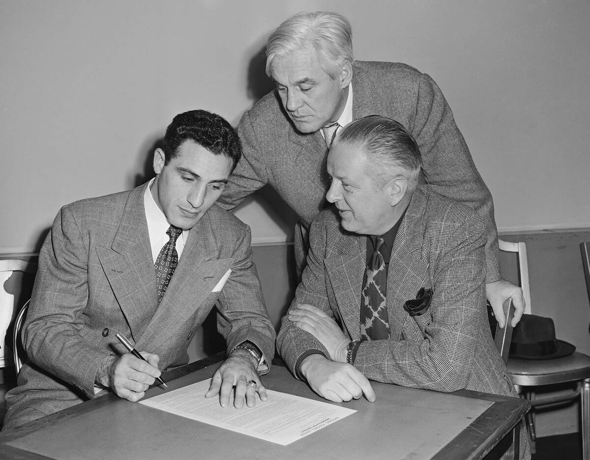 Charley Trippi, left, Georgia football star, signs his $100,000 with Chicago Cardinals at Chica ...