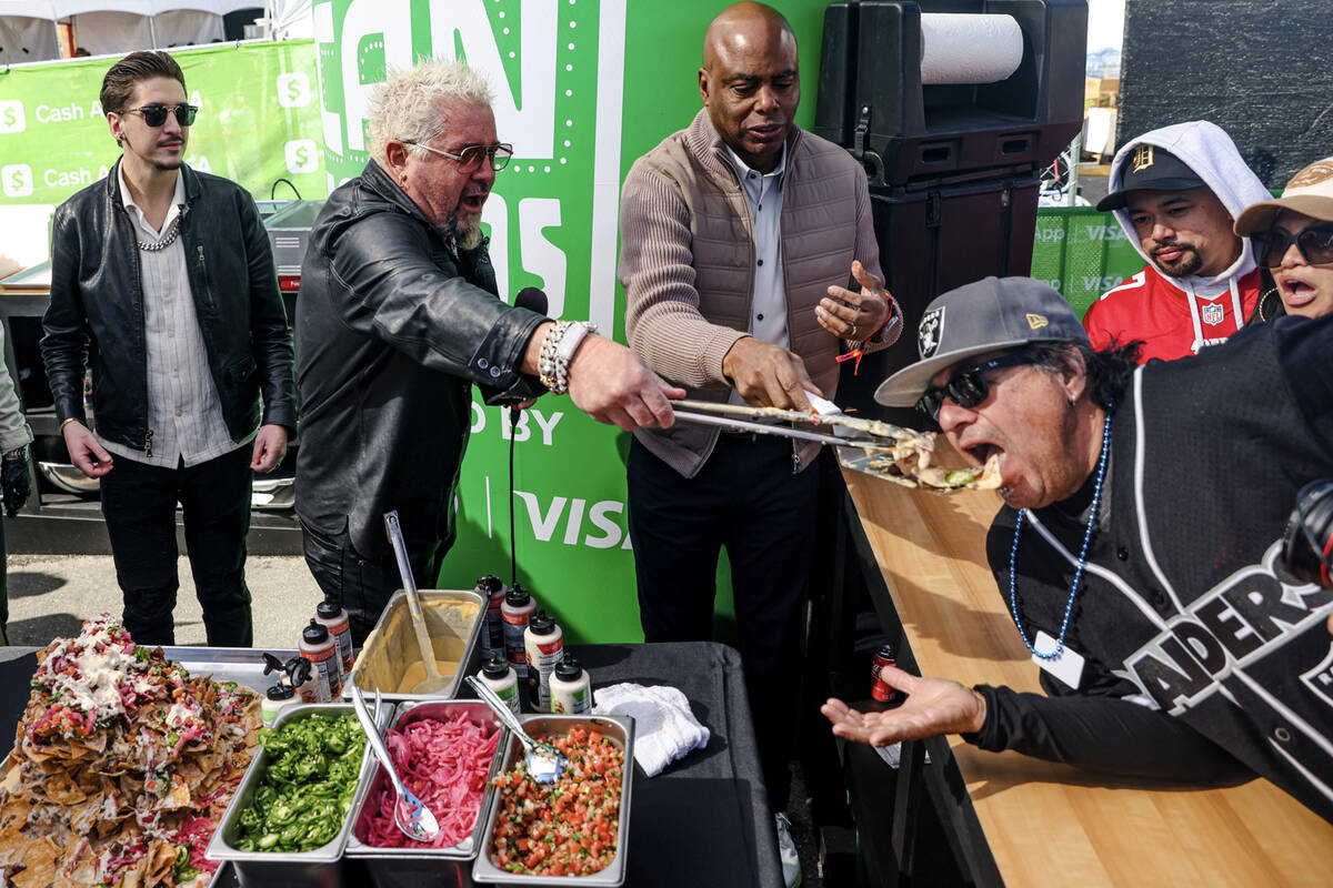 Celebrity chef Guy Fieri feeds a serving of trash can nachos to David Ortiz, from Los Angeles, ...