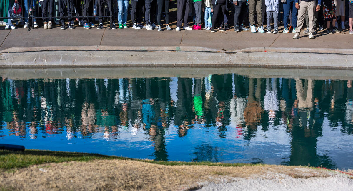 The crowd is reflected in the water as they gather for the finish about hole #18 during the fin ...