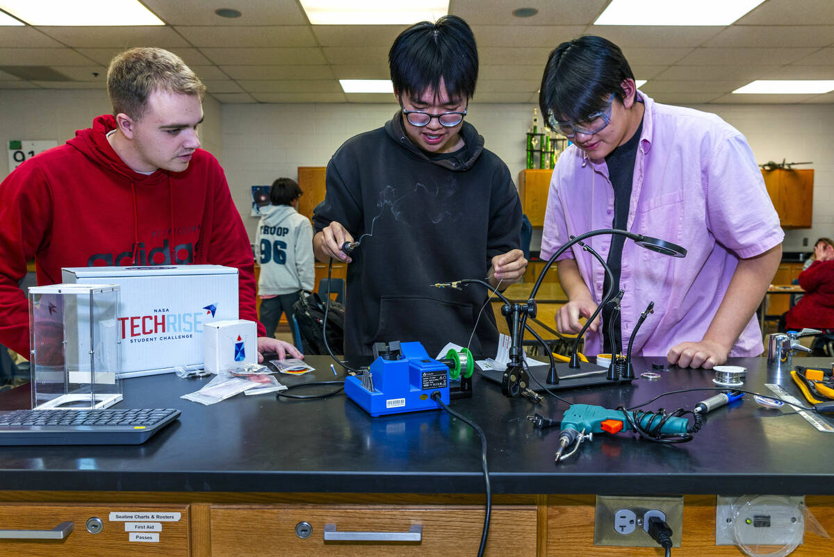 (LtoR) Students Kyle Hickman, Derek Feng and Brian Luong practice soldering an electronic bug a ...