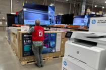 An associate checks over a big-screen television on display in a Costco warehouse Tuesday, Feb. ...