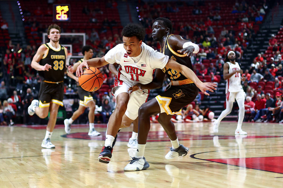UNLV Rebels guard Dedan Thomas Jr. (11) drives toward the hoop around Wyoming Cowboys guard Aku ...