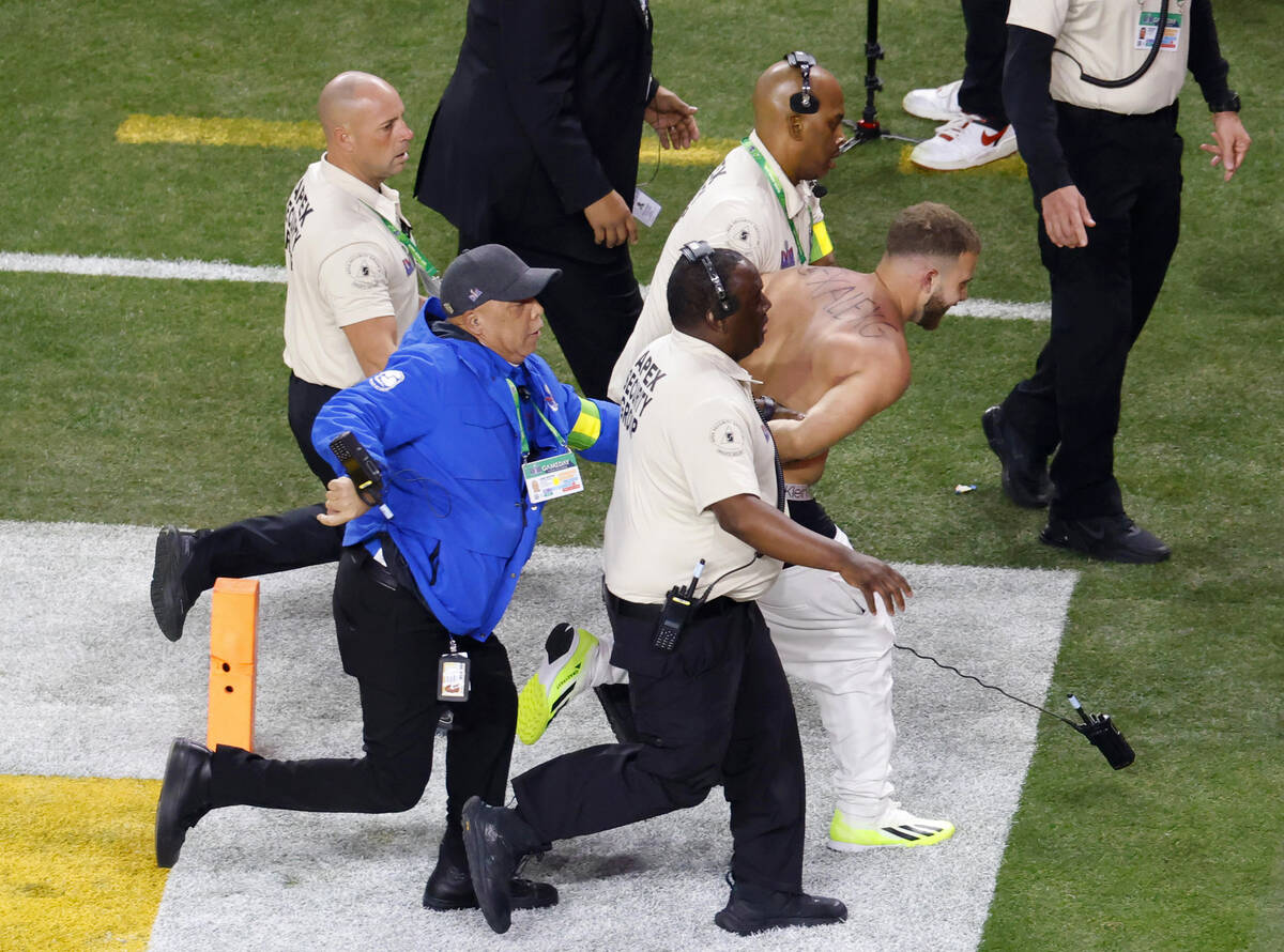 A shirtless Alex Gonzalez is escorted away by security after running on the field during Super ...