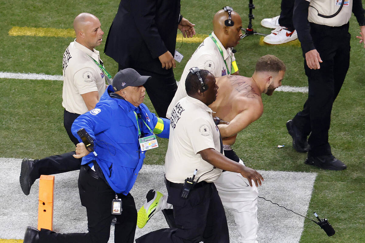 A shirtless Alex Gonzalez is escorted away by security after running on the field during Super ...