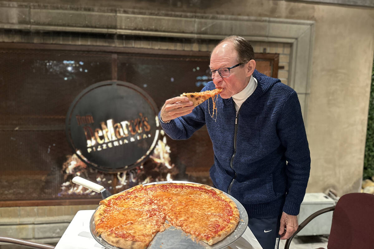 Albert Scalleat, owner of Dom DeMarco's Pizzeria & Wine Bar in Las Vegas, tucks into an 18- ...