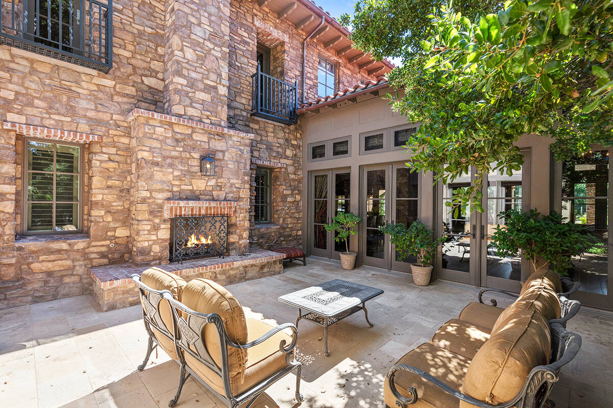 The Southern Highlands Tuscan-designed home features lush landscaping and a patio with a firepl ...