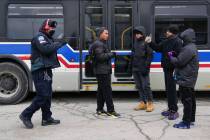 A Chicago Transit Authority worker, left, greets migrants where "warming" buses are p ...