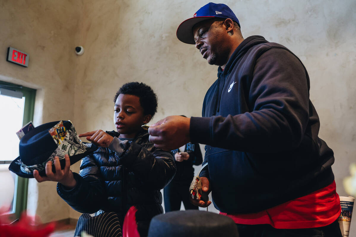 Lyonel Loundermon, right, puts a decoration on a hat for his son, Daniel, 9, at a craft table a ...