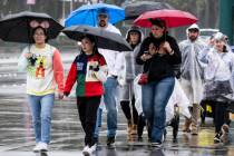 People walk with umbrellas and ponchos in the resort district near Disneyland in Anaheim, Calif ...