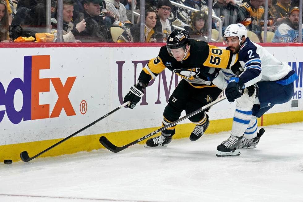 Pittsburgh Penguins' Jake Guentzel (59) reaches for a loose puck in front of Winnipeg Jets' Dyl ...