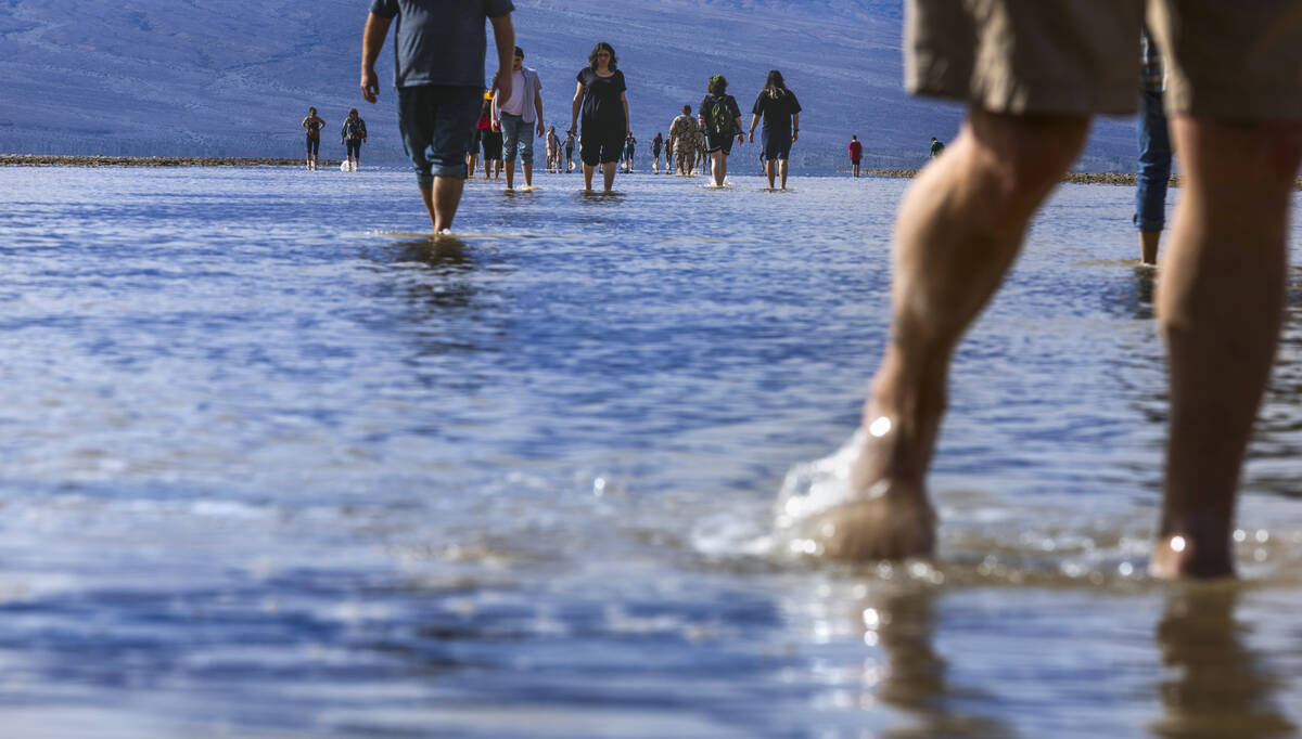 People wander in and out of the water on the temporary Lake Manly at Badwater Basin in Death Va ...