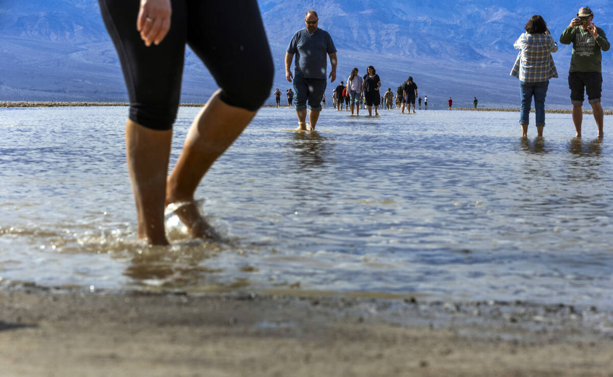 People wander in and out of the water on the temporary Lake Manly at Badwater Basin in Death Va ...