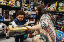 Katie Krikorian, right, holds out a toy for her adopted son, Isaac Krikorian, 1, at Peggy&#x201 ...