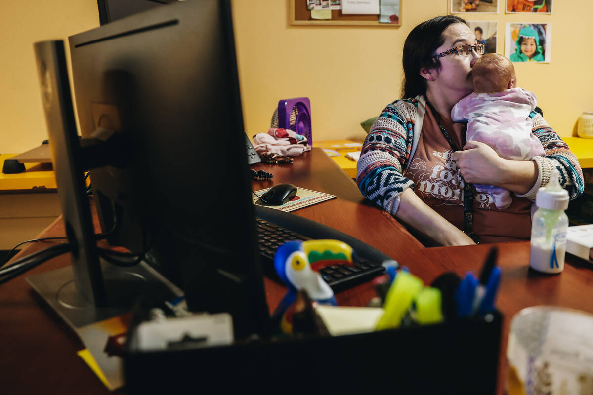 Katie Krikorian holds one of her foster children while sitting at her desk on the Child Haven c ...