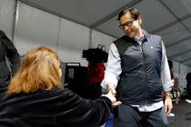Secretary of State Cisco Aguilar shakes hands with poll worker Esmeralda Reynold during primary ...