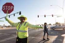 Crossing guard Patricia Bass assists a child in crossing Lake Mead Boulevard at Tonopah Drive i ...