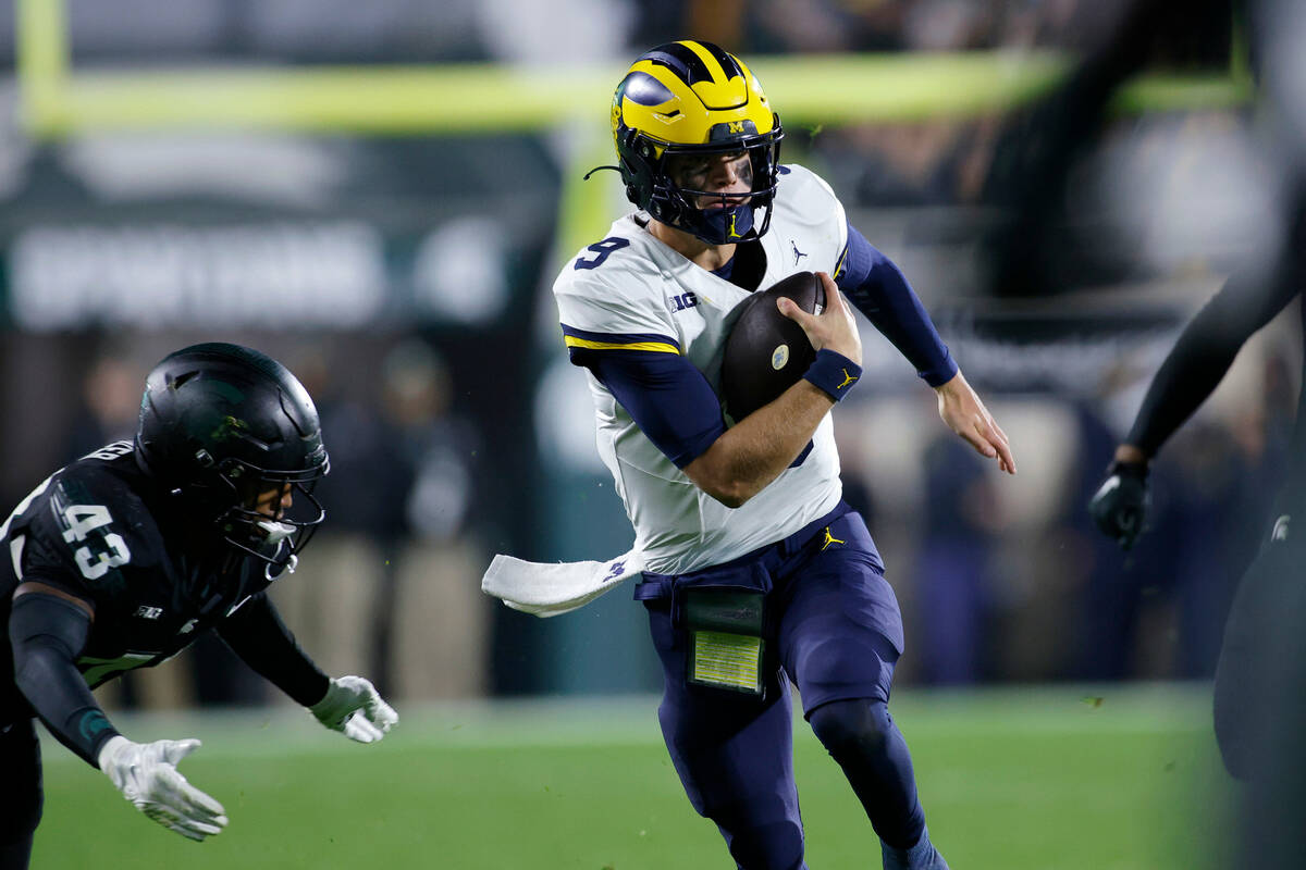 Michigan quarterback J.J. McCarthy, right, scrambles against Michigan State defensive back Mali ...