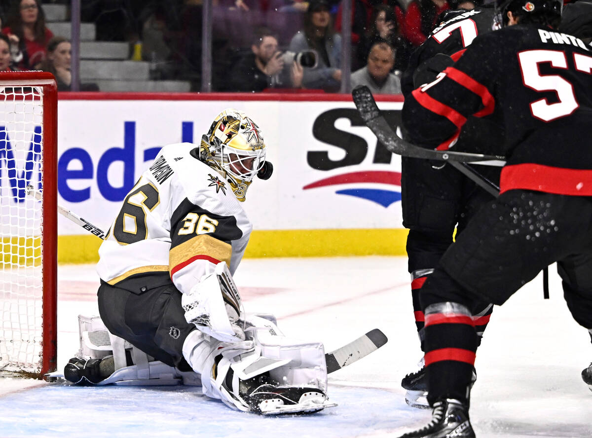 The puck bounces off the mask of Vegas Golden Knights goaltender Logan Thompson (36) during the ...