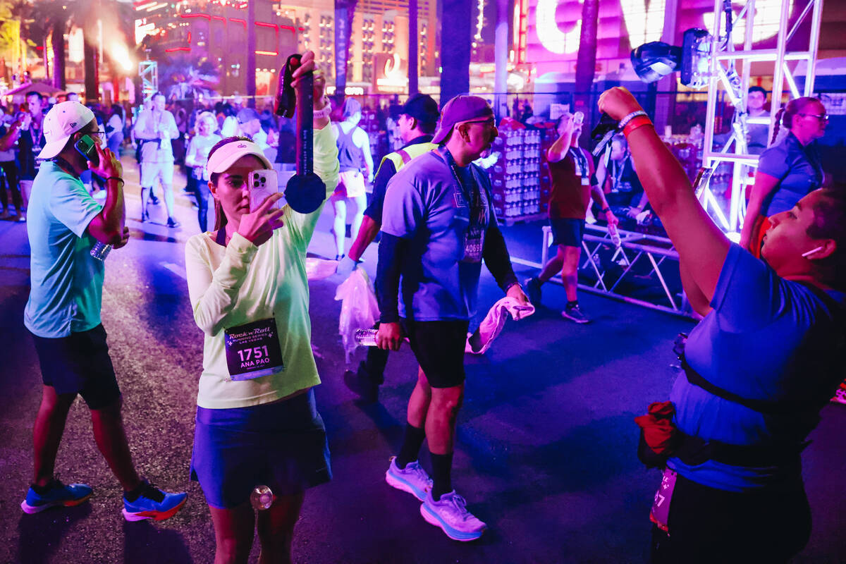 Runners take photos of their medallions during the Rock ’n’ Roll Running Series o ...