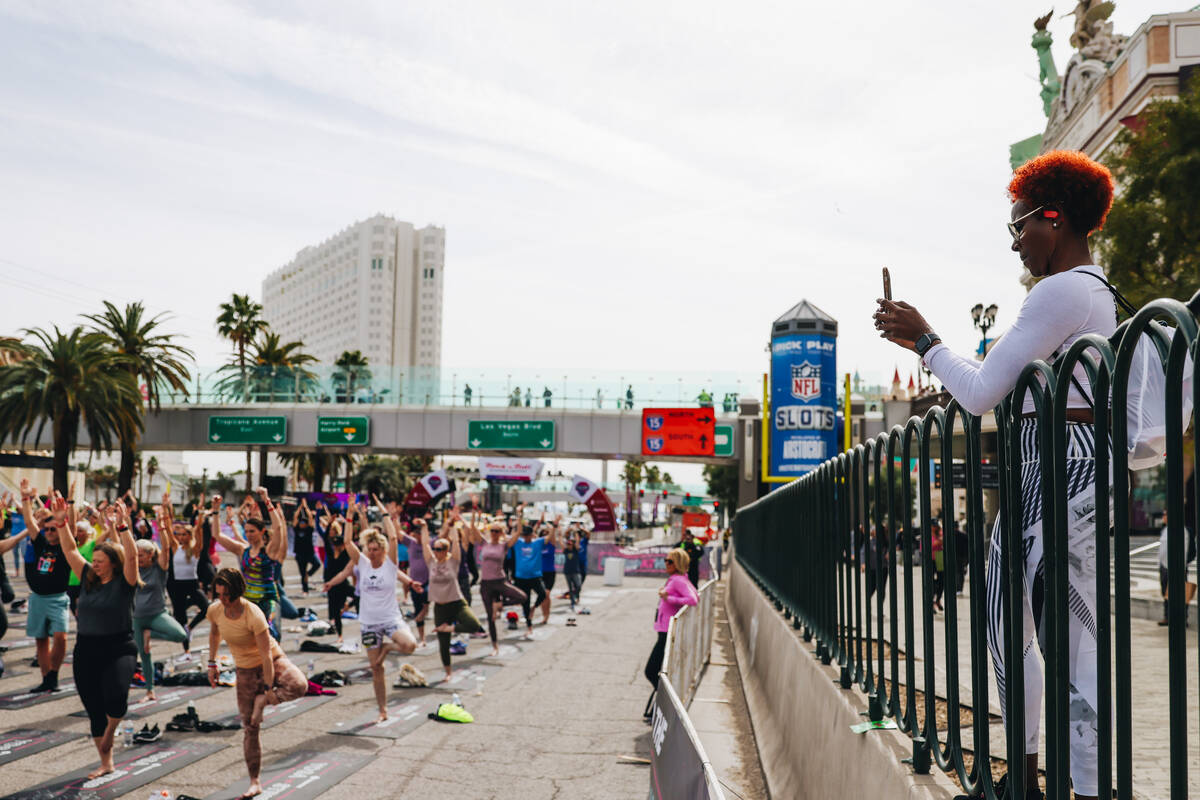 A person takes photos of people gathering on the Strip to do yoga while it is shut down for the ...
