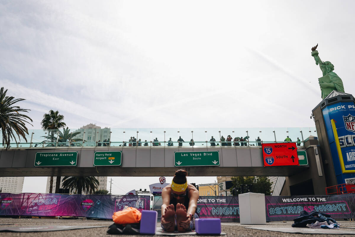 Spectators on a pedestrian bridge watch as people do yoga on the Strip while it is shut down fo ...