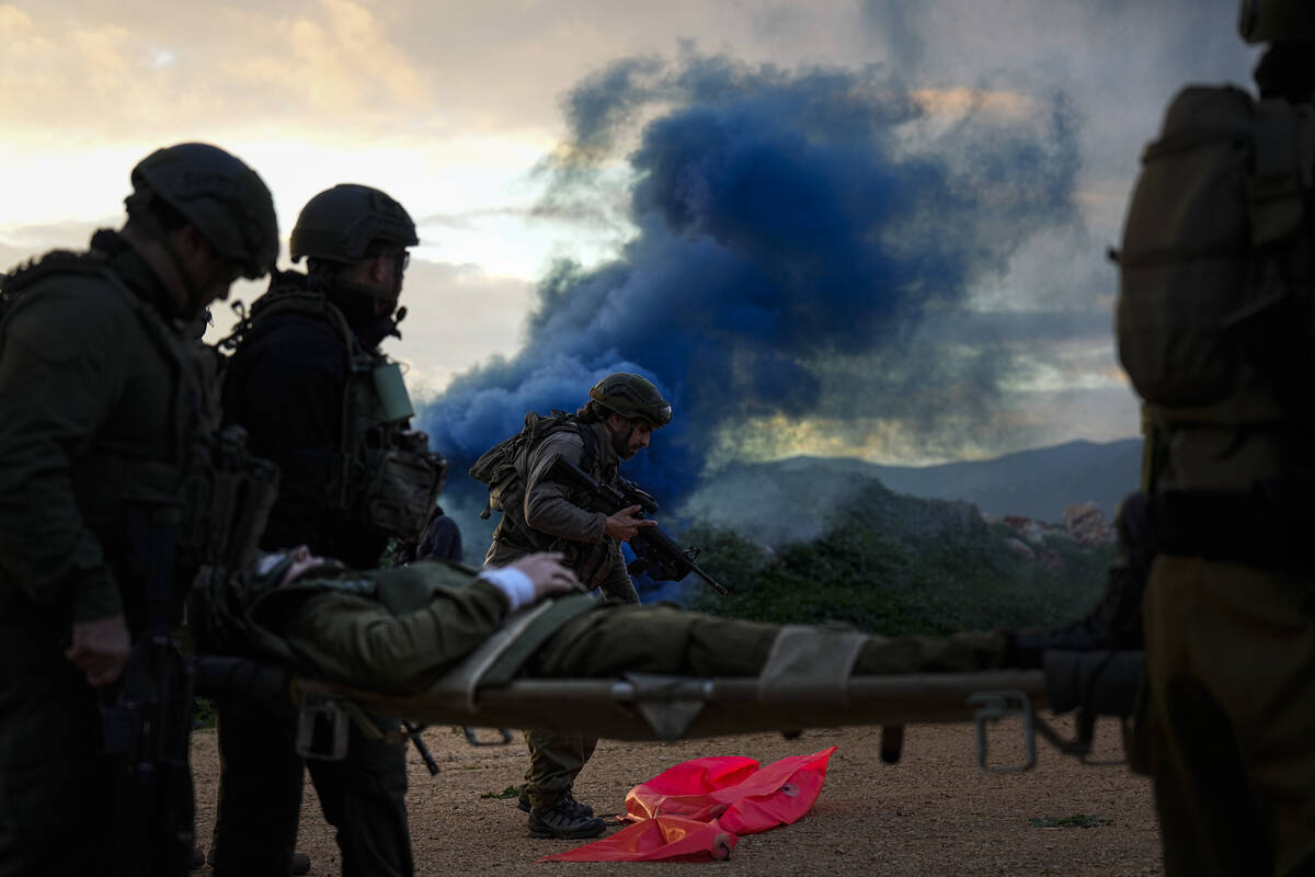 Israeli soldiers run as they carry a stretcher towards a military helicopter during an exercise ...