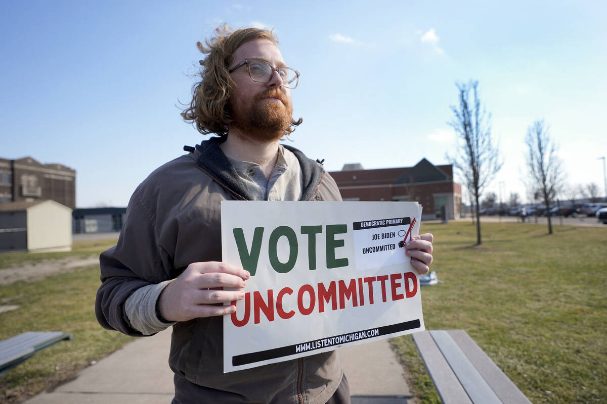 Eric Suter-Bull holds a Vote Uncommitted sign outside a voting location at Saline Intermediate ...