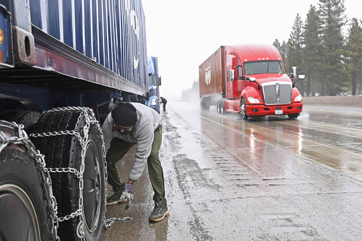 Mangal Singh parks his truck off the I-80 to put chains on his truck wheels in preparation for ...