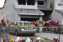 Flowers, stuffed animals and candles are placed on and along a chain-link fence in a makeshift ...