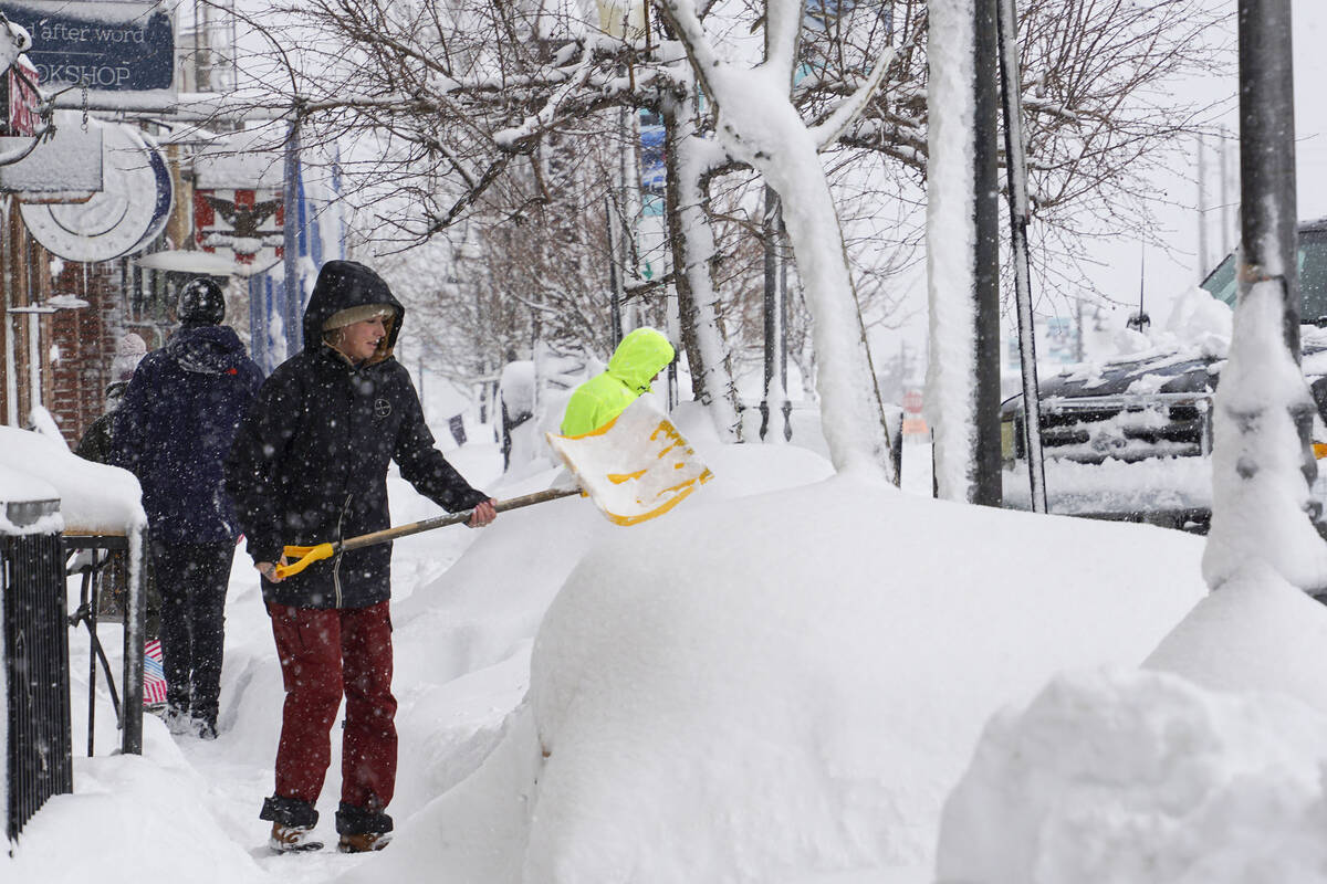 Snow is cleared from sidewalks in front of business during snow storm, Saturday, March 2, 2024, ...