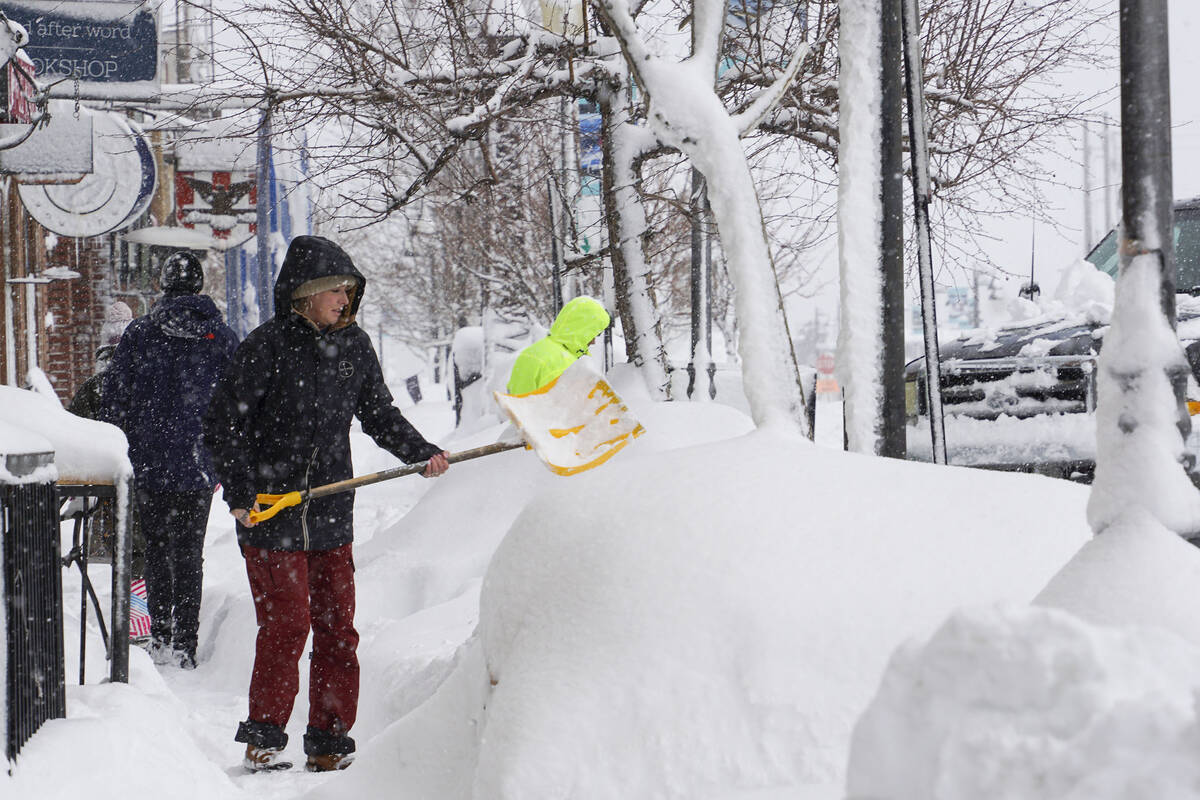 Snow is cleared from sidewalks in front of business during snow storm, Saturday, March 2, 2024, ...