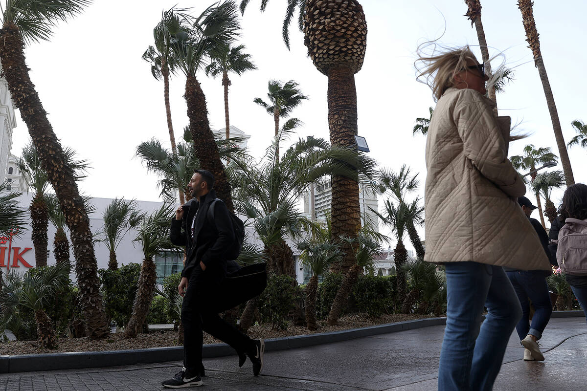 Visitors to the Las Vegas Strip traverse Las Vegas Boulevard as a high wind warning is in effec ...