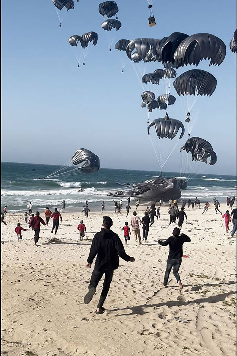 This image grab from an AFPTV video shows Palestinians running toward parachutes attached to fo ...