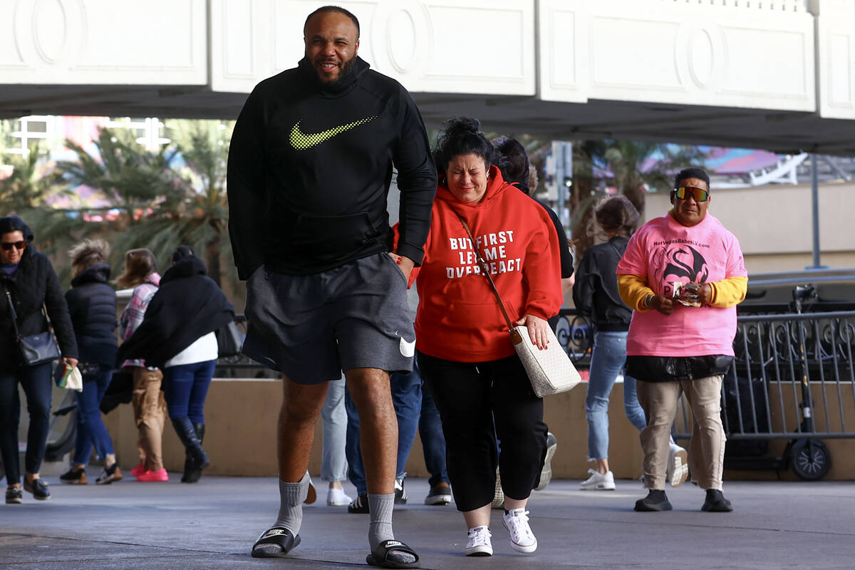 Visitors to the Las Vegas Strip brace themselves as a high wind warning is in effect on Saturda ...