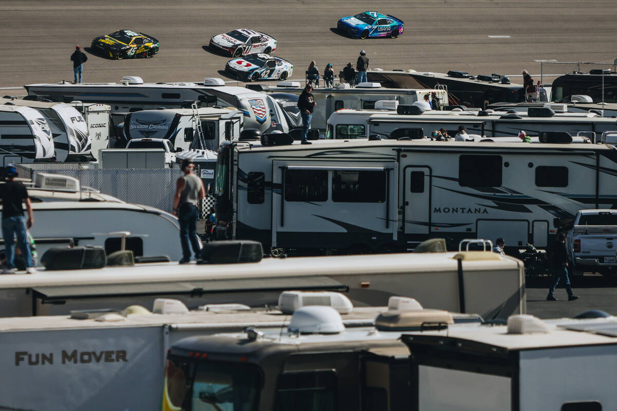 Fans in an area for recreational vehicles watch as race cars speed by them at the Pennzoil 400 ...