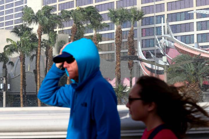 Visitors to the Las Vegas Strip walk on Las Vegas Boulevard despite a high wind warning on Satu ...