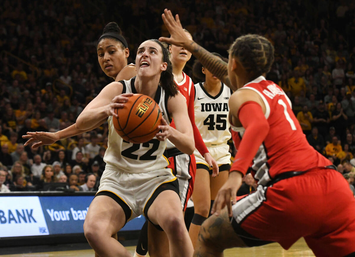 Iowa guard Caitlin Clark (22) drives to the basket between Ohio State guard/forward Taylor Thie ...
