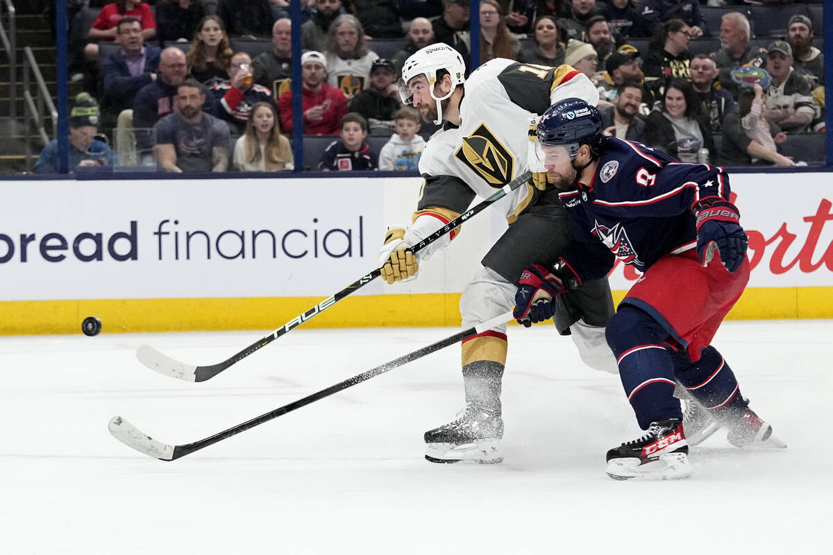 Vegas Golden Knights center Nicolas Roy, left, shoots next to Columbus Blue Jackets defenseman ...