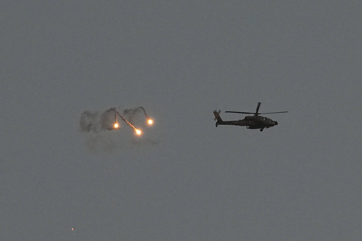 An Israeli Apache helicopter fires flares over the Gaza Strip as seen from southern Israel, Mon ...