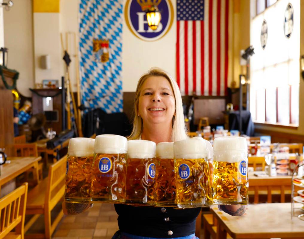 Roxy, a server and restaurant supervisor, holds glasses of beer as she poses for a photo at Hof ...