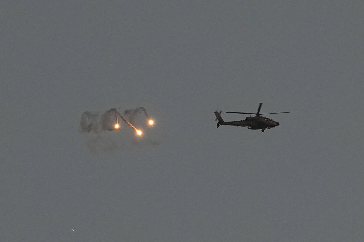 An Israeli Apache helicopter fires flares over the Gaza Strip as seen from southern Israel, Mon ...
