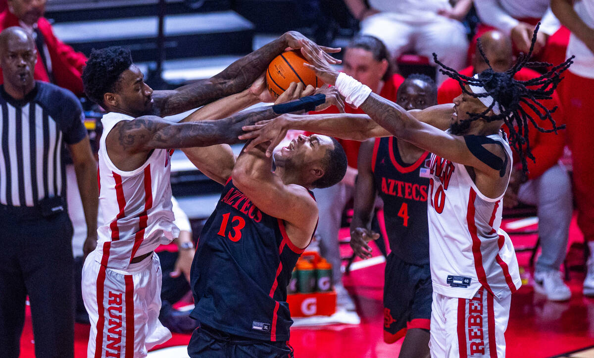 UNLV forward Keylan Boone (20) and forward Kalib Boone (10) reject a shot attempt by San Diego ...