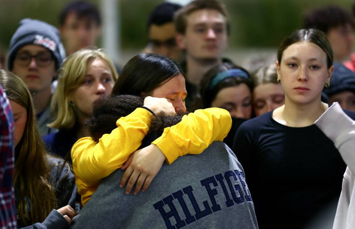 Paige Oden, center left, and Sana’a Wong embrace during a vigil for their former teammate, st ...