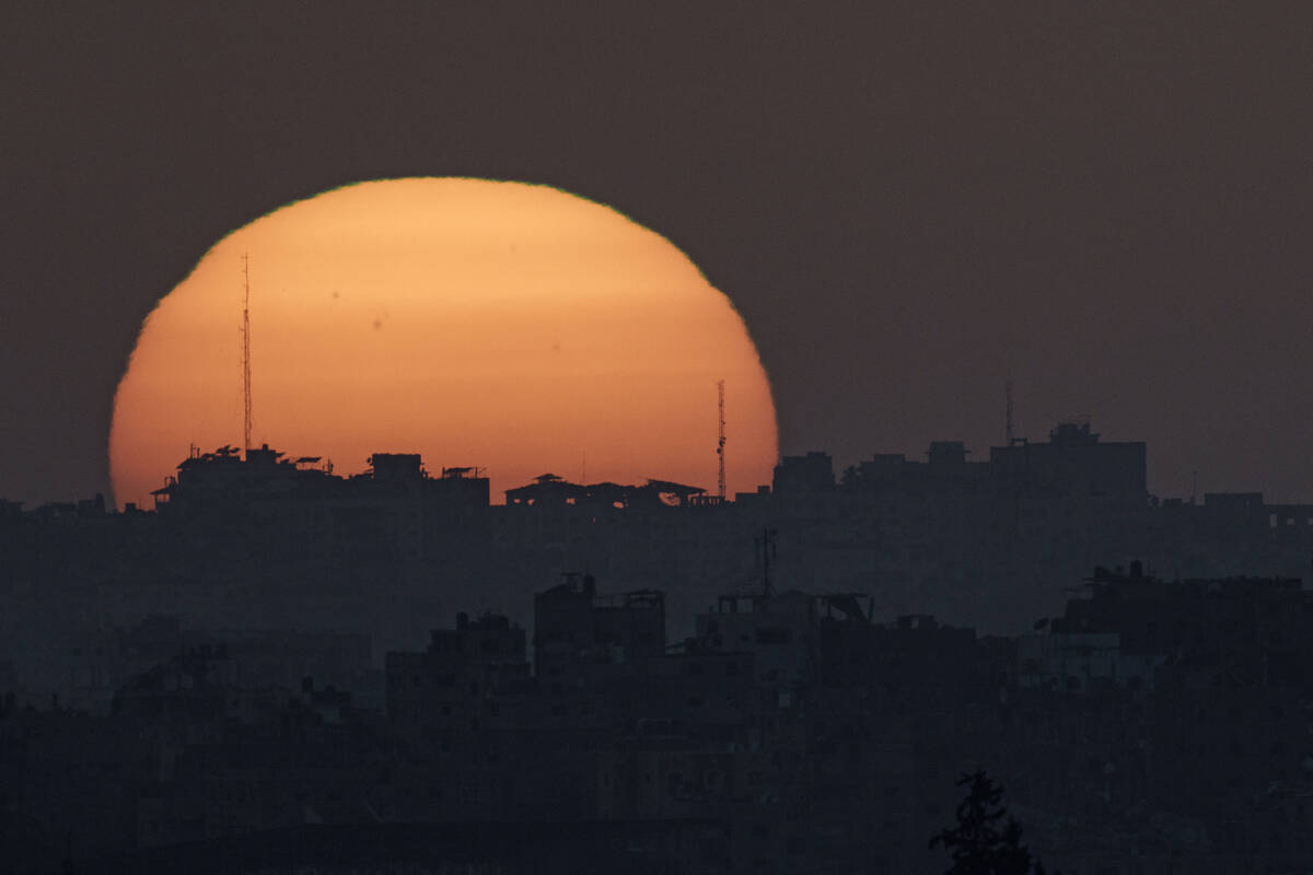 The sun sets behind the buildings in the Gaza Strip as seen from southern Israel, Tuesday, Marc ...
