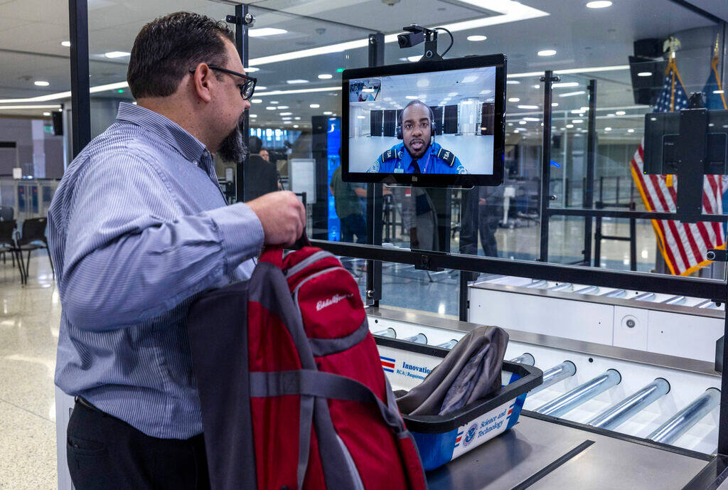 A Transportation Security Administration employee gets instructions from a TSA agent on screen ...