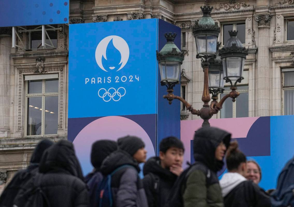 Youth gather at Paris City Hall where a Paris 2024 Olympic sign is displayed in Paris, Tuesday, ...