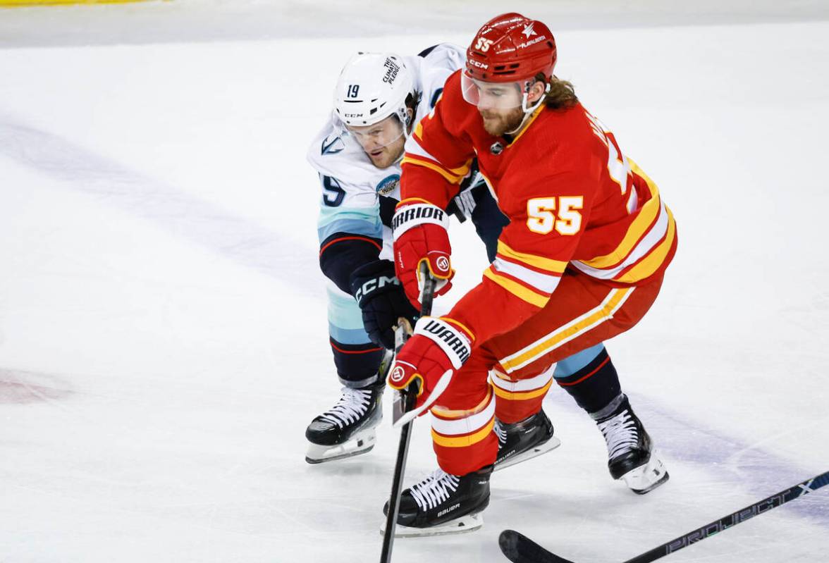 Seattle Kraken forward Jared McCann (19) checks Calgary Flames defenseman Noah Hanifin (55) dur ...