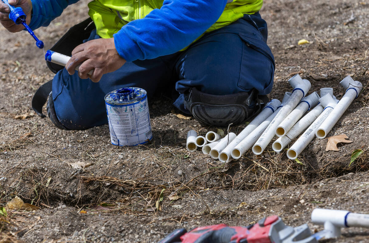 A crew from Park West is lays down irrigation lines for new desert landscaping, plants and tree ...