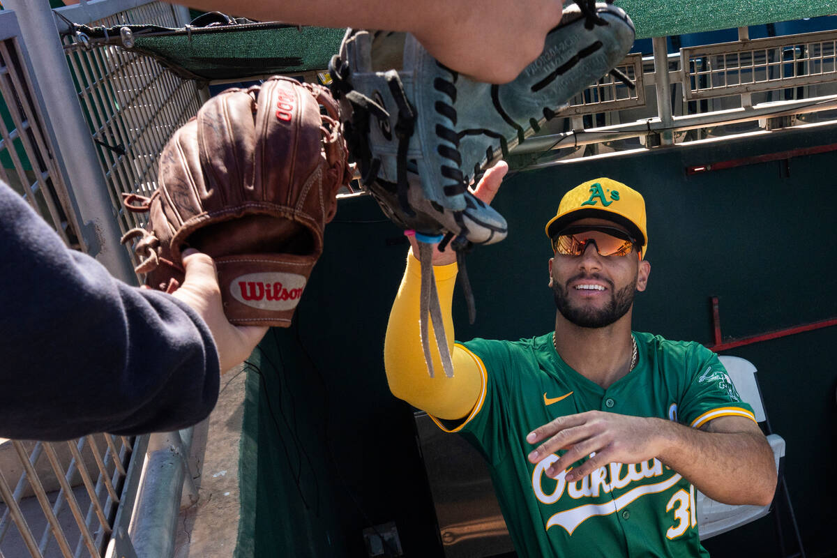 Oakland Athletics' Abraham Toro, right, autographs baseball gloves before a spring training bas ...